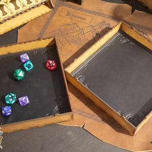May include: A wooden dice tray with a black felt insert and a set of colorful dice. The tray has a decorative border and is made of light wood. The dice are scattered on the felt insert.