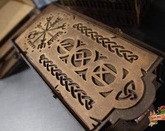 May include: A rectangular brown wooden box featuring intricate laser-cut designs on its lid. The top surface displays a compass symbol, a central row of circular geometric patterns, and braided border details. The box has a dark finish.