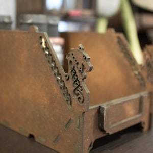 May include: A wooden box with a dragon design. The box has a hinged lid and is made of dark brown wood. The dragon design is carved into the wood and is painted in a light brown colour.