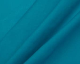 May include: A close-up shot of a folded piece of teal fabric. The fabric has a smooth texture and is draped in diagonal folds, creating shadows and highlights. The color is a vibrant, solid teal, with no visible patterns or designs.
