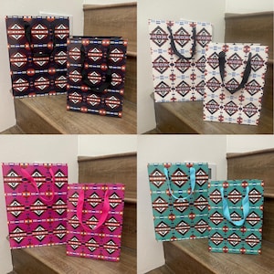 May include: Set of six gift bags with geometric patterns. The bags are in various colors, including black, white, red, blue, green, and pink. Each bag has a black or blue handle.