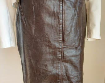 May include: A brown leather skirt with a straight cut and a zipper detail at the back.
