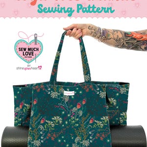 May include: A teal Yoga Tote Grande sewing pattern with a floral design. The tote bag has a black yoga mat inside. The text "Yoga Tote Grande Sewing Pattern" is at the top of the image. The bag is held by a person.