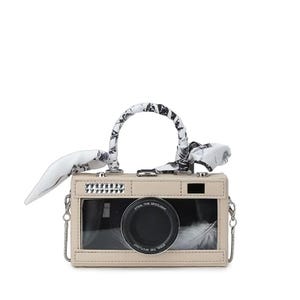 Peut inclure: Un sac à main beige en forme d'appareil photo avec un objectif noir et une poignée enveloppée dans un tissu à motifs noir et blanc. Le sac a une fenêtre transparente et une bandoulière en chaîne argentée. Le texte "STEAL THE SPOTLIGHT" est visible sur l'objectif.