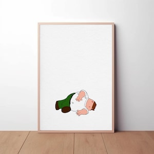 Peut inclure: Une affiche encadrée représentant un personnage de dessin animé allongé. Le personnage porte une chemise blanche, un pantalon vert et des chaussures marron. L'affiche est dans un cadre marron clair, sur fond blanc.