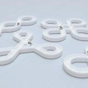 May include: White plastic infinity-shaped marble tracks with small silver metal balls inside. The tracks are arranged in a group on a light blue surface. The tracks are a toy or puzzle.