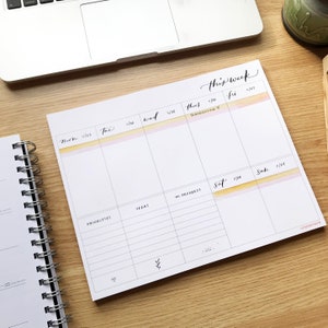 May include: A weekly planner with a watercolor background in shades of yellow and pink. The planner has sections for each day of the week, with spaces for "priorities", "ideas", and "in progress". The text "this week" is written at the top of the planner.