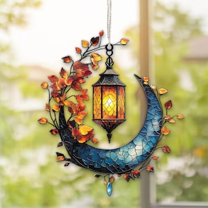 May include: A decorative hanging lantern with a crescent moon design. The lantern has a warm, glowing light and is surrounded by a blue mosaic moon and autumn-colored leaves. A small, blue gem hangs from the bottom.