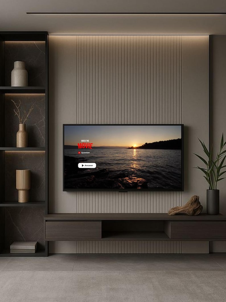 May include: A wall-mounted television displaying a sunset over water with the text Guess the Movie, Question, and Answer. The screen is centred on a vertical-slatted beige wall above a dark wood media console with open shelving and decor.