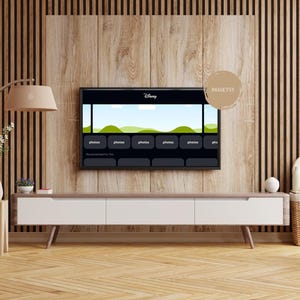 May include: A flat screen television with a black frame is mounted on a wood wall. The screen displays the Disney+ logo and a row of icons for different shows. The television is mounted above a white entertainment center with a wood top. The entertainment center is in front of a wood wall with vertical slats.