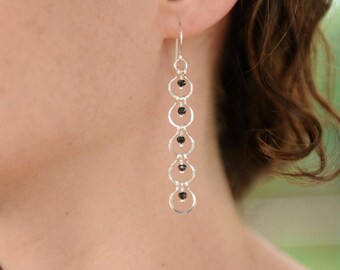 May include: Silver dangle earrings with black beads and a chain-like design.