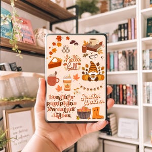 Può includere: Uno schermo di tablet mostra illustrazioni a tema autunnale, tra cui una fetta di torta, caffè, zucche e le parole "hello fall". Altri testi includono "bonfires", "pumpkins", "sweaters" e "lattes". La tavolozza dei colori presenta arancioni, marroni e creme caldi.