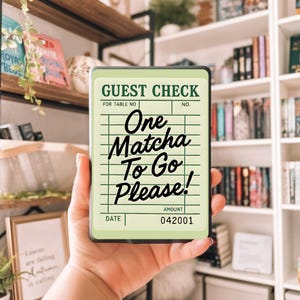 May include: A light green guest check with the text "One Matcha To Go Please!" in black script. The check has a grid pattern and the words "GUEST CHECK" at the top. The amount is listed as 042001.