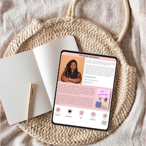May include: A pink and white digital tablet displaying a book cover with the title "inks & heartbreaks". The book cover features a couple with a pink and blue background. The tablet also displays the author's name, Helena Sanders, and a description of the book. The tablet is on a woven straw bag.