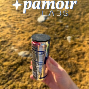 May include: A silver and blue can with a black lid, held in a hand. The can has nutritional information and the text "160". The image also includes the text "pamoir LABS".