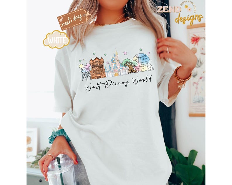 May include: White t-shirt featuring a colorful illustration of the Walt Disney World skyline. The design includes iconic landmarks like Cinderella Castle and Spaceship Earth, with the words "Walt Disney World" in a script font.