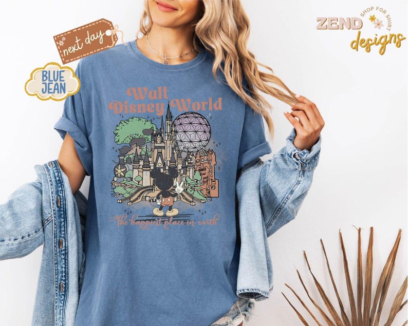 以下が含まれることがあります： ウォルト・ディズニー・ワールドのグラフィックがプリントされた青いTシャツ。お城、スペースシップ・アース、ミッキーマウスが描かれています。「Walt Disney World」と「The happiest place on earth」の文字がプリントされています。ヴィンテージ風のTシャツです。