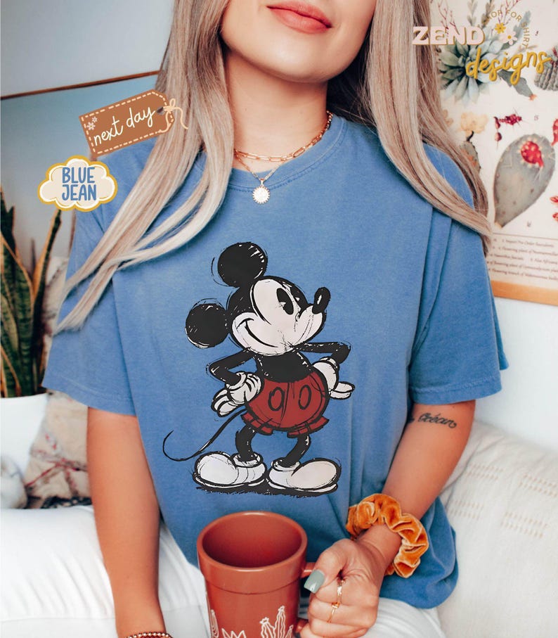 May include: A blue t-shirt with a black and white cartoon image of Mickey Mouse. Mickey Mouse is wearing red shorts with white polka dots. The t-shirt has a distressed look.