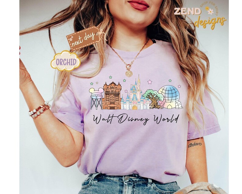 May include: A light purple t-shirt featuring a colorful illustration of Walt Disney World landmarks, including Cinderella's castle and Spaceship Earth. The words "Walt Disney World" are written in a script font below the illustration.