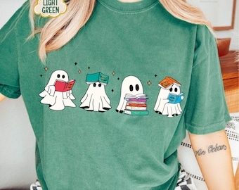 Op de afbeelding: Een groen T-shirt met een afbeelding van vier geesten die boeken lezen. De geesten zijn wit en hebben zwarte ogen. De boeken zijn in verschillende kleuren en hebben titels zoals "Het Boek der Spreuken" en "De Geesten Gids".