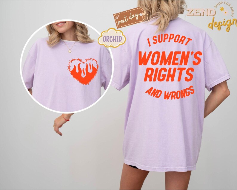 May include: A lavender t-shirt with the text "I support women's rights and wrongs" printed in orange on the back. The front of the shirt features a barbed wire heart with flames inside, also in orange.