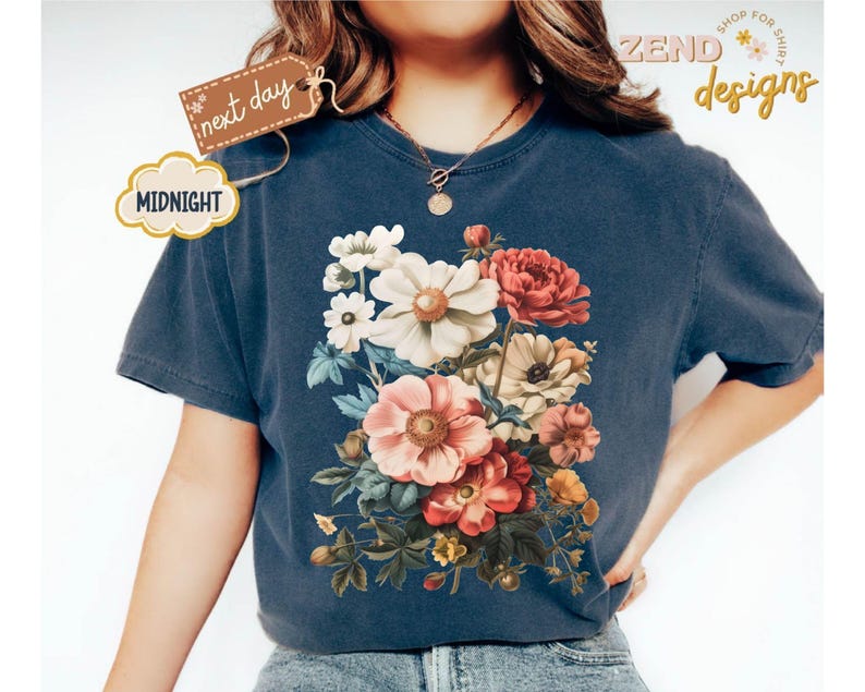 Puede incluir: Una camiseta azul marino con un dise&ntilde;o de ramo floral en tonos blancos, rosas y rojos. La camiseta tiene cuello redondo y mangas cortas. El texto "next day" y "Midnight" est&aacute; en la camiseta.