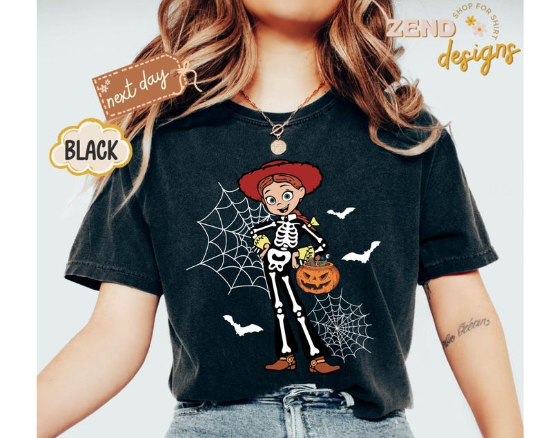 K&ouml;nnte beinhalten: Schwarzes T-Shirt mit einem Halloween-Motiv. Das Design zeigt ein Cartoon-Skelett, das als Cowgirl verkleidet ist und einen K&uuml;rbis-Eimer h&auml;lt, mit Spinnweben und Flederm&auml;usen. Das Shirt hat den Text "next day" und "BLACK".