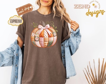 May include: A brown t-shirt with a patchwork pumpkin design. The pumpkin features various patterns and a pink bow. The shirt has the word "Espresso" and "next day" on it. The words "Zend designs" are also visible.