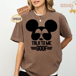 Puede incluir: Una camiseta marr&oacute;n de manga corta con un gr&aacute;fico negro de la silueta de un rat&oacute;n con gafas de sol. Debajo del gr&aacute;fico, el texto "TALK TO ME GOOF" aparece en letras may&uacute;sculas negras, flanqueado por dos l&iacute;neas horizontales a cada lado de GOOF.