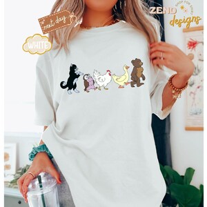 May include: White t-shirt featuring a line of cartoon animals: a black cat, an owl, a chicken, a duck, and a bear. The shirt has the word "WHITE" in a bubble and a tag that says "next day".
