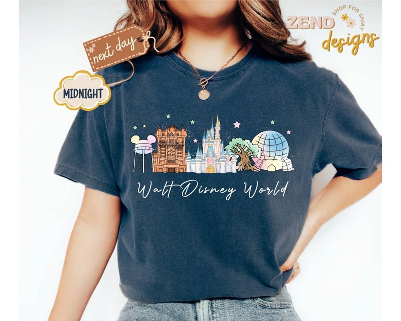 May include: Navy blue t-shirt featuring a colorful illustration of Walt Disney World landmarks, including Cinderella's castle and Spaceship Earth. The text "Walt Disney World" is printed below the graphic. A tag reads "next day" and a cloud reads "MIDNIGHT".