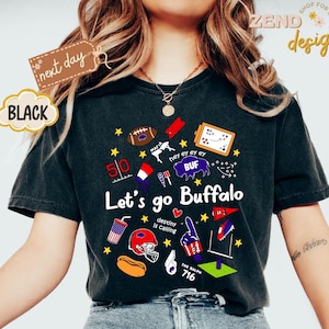 May include: Black t-shirt with a graphic design featuring the text "Let's go Buffalo" and various sports-themed illustrations. Includes a football, helmet, and the number 716. The shirt also has the text "next day" and "BLACK".