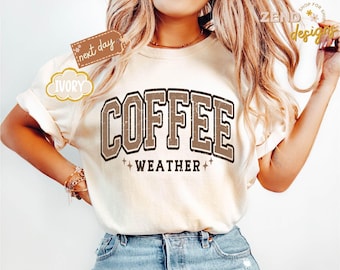 Könnte beinhalten: Cremefarbenes T-Shirt mit dem Text "COFFEE WEATHER" in verblichener brauner Schrift. Das Design hat einen Vintage-Look, mit Rundhalsausschnitt und kurzen Ärmeln. Der Text ist von einem braunen Rand und Sternen umgeben.