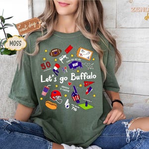 May include: Green t-shirt with the text "Let's go Buffalo" and various graphics, including a football, stars, and a helmet. The shirt also features the number 50 and the text "The Ralph 716".