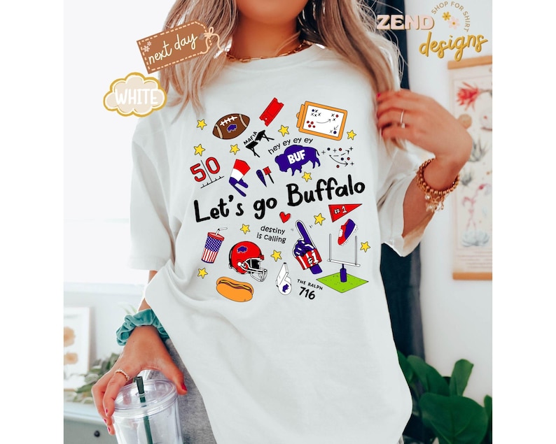 May include: White t-shirt with a colorful graphic design featuring the text "Let's go Buffalo" and various sports-themed illustrations. The design includes a football, helmet, and the number 716.