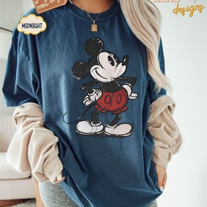 May include: A blue t-shirt with a vintage-style Mickey Mouse graphic. The shirt is oversized and has a relaxed fit.