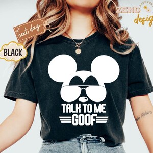 Puede incluir: Una camiseta negra de manga corta con un gr&aacute;fico blanco de la silueta de un rat&oacute;n con gafas de sol. Debajo del gr&aacute;fico, el texto dice TALK TO ME GOOF con l&iacute;neas horizontales encima y debajo de la palabra GOOF. La camiseta tiene cuello redondo.