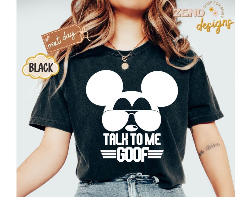 Puede incluir: Una camiseta negra de manga corta con un gr&aacute;fico blanco de la silueta de un rat&oacute;n con gafas de sol. Debajo del gr&aacute;fico, el texto dice TALK TO ME GOOF con l&iacute;neas horizontales encima y debajo de la palabra GOOF. La camiseta tiene cuello redondo.