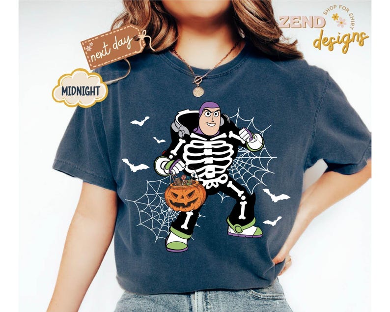 K&ouml;nnte beinhalten: Dunkelblaues T-Shirt mit einem Halloween-Motiv von Buzz Lightyear. Die Grafik zeigt Buzz Lightyear in einem Skelettkost&uuml;m, der einen K&uuml;rbis mit sich tr&auml;gt. Wei&szlig;e Spinnweben und Flederm&auml;use sind ebenfalls im Design enthalten. Das Shirt hat den Text "Midnight" und "next day".