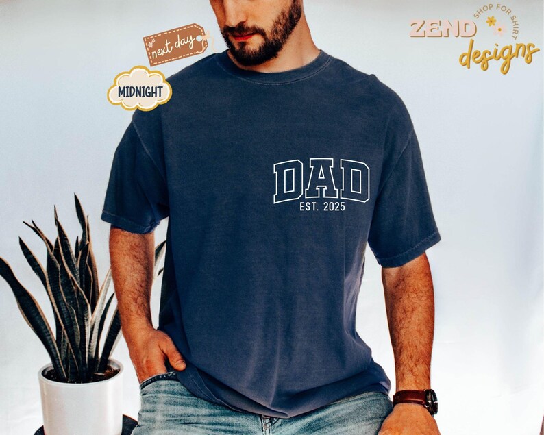 May include: A navy blue t-shirt with white text that reads "DAD EST. 2025".