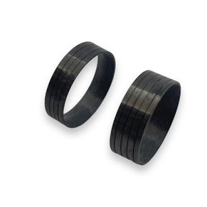 May include: Two black carbon fibre rings with a grooved design. The rings are stacked on top of each other.