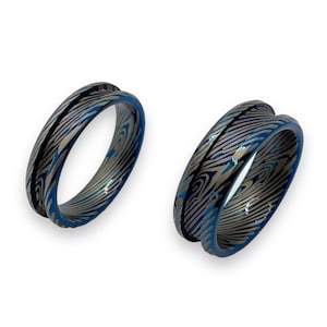 May include: Two blue and silver patterned rings with a beveled edge. The rings are made of metal and have a unique, swirling design.