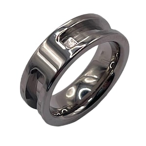 May include: A silver ring with a single diamond set in the center. The ring has a unique design with a groove running around the band.