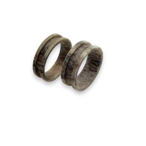 May include: Two wooden rings with a natural wood grain finish. The rings are stacked on top of each other.
