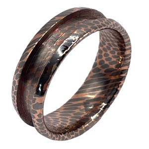 May include: A copper ring with a textured, patterned design. The ring has a wide band and a polished finish.