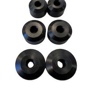 May include: Six black rubber spacers with a central hole. The spacers are of different sizes, with the two largest being flat and the four smaller ones being slightly rounded.