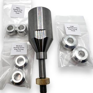 May include: A set of three metal ring turning chucks with different sized bushings. The chucks are silver and the bushings are silver. The chucks are labeled "Small", "Medium", and "Large".