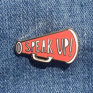 以下が含まれることがあります： 「Speak Up!」という白い文字が書かれた、メガホン型の赤いエナメルピンです。