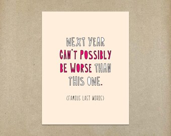 May include: A white card with black and pink text that reads "NEXT YEAR CAN'T POSSIBLY BE WORSE THAN THIS ONE. (FAMOUS LAST WORDS)"