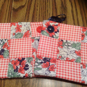 May include: Two red and white gingham patchwork pot holders with floral designs. One pot holder has a blue button.